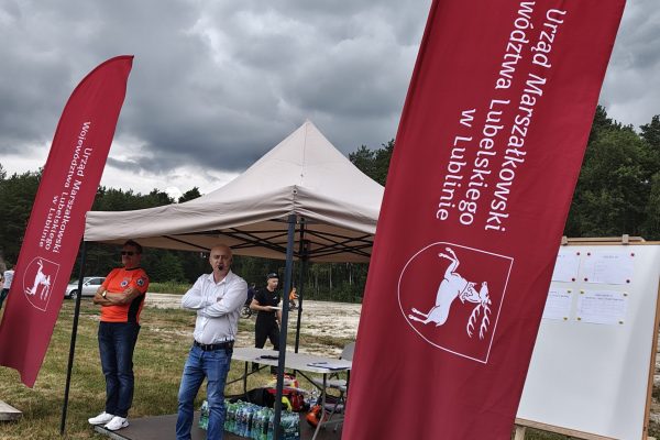 Plenerowe stoiska i dekoracje przy boisku turnieju piłki błotnej.