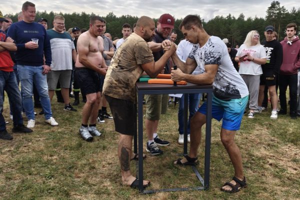 Uczestnicy turnieju przy drewnianym stoliku na terenie imprezy.