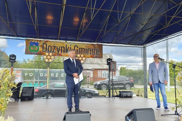 Wystąpienie przy mikrofonie na plenerowej scenie dożynek.