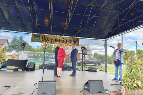 Wystąpienie przy mikrofonie na plenerowej scenie dożynek.
