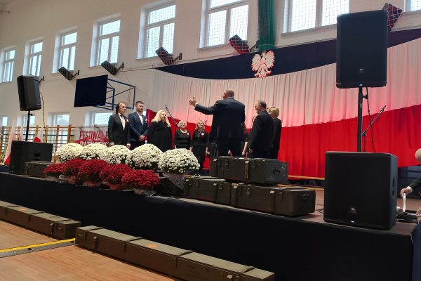 Uczestnicy przy mikrofonach na scenie Festiwalu Pieśni Patriotycznych.