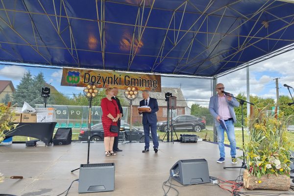 Wystąpienie przy mikrofonie na plenerowej scenie dożynek.