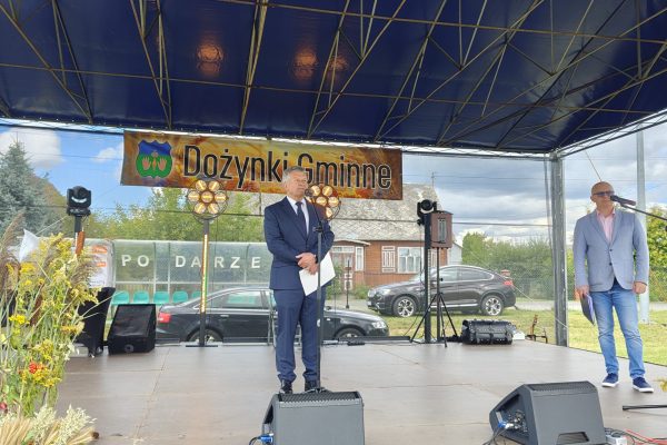 Wystąpienie przy mikrofonie na plenerowej scenie dożynek.