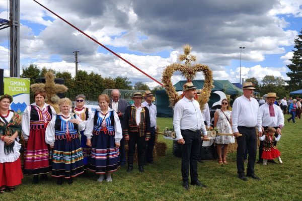 Korowód dożynkowy z wieńcami i uczestnikami w strojach ludowych.