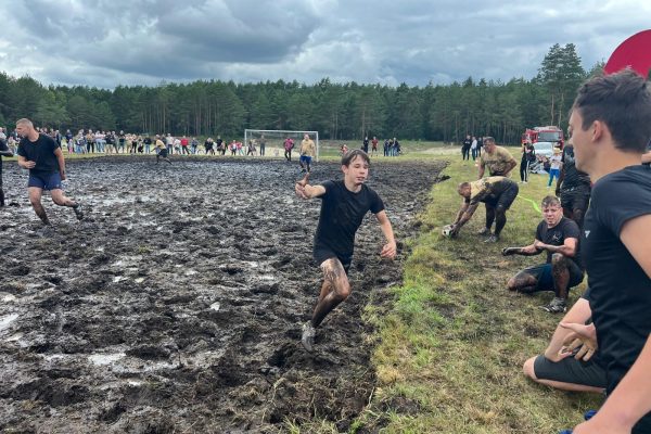 Zawodnicy podczas meczu piłki błotnej na mokrym, błotnistym boisku.
