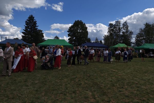 Korowód dożynkowy z wieńcami i uczestnikami w strojach ludowych.