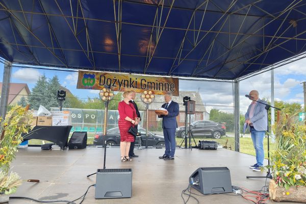 Wystąpienie przy mikrofonie na plenerowej scenie dożynek.