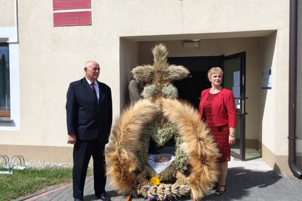 Uczestnicy dożynek z wieńcami i tabliczkami przed kościołem.