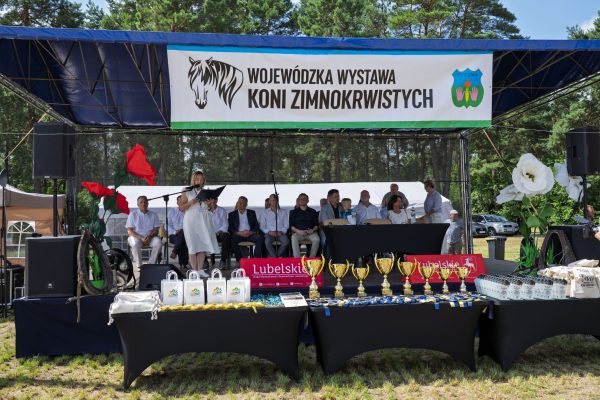 Scena z banerem Wojewódzkiej Wystawy Koni Zimnokrwistych i stołem nagród.