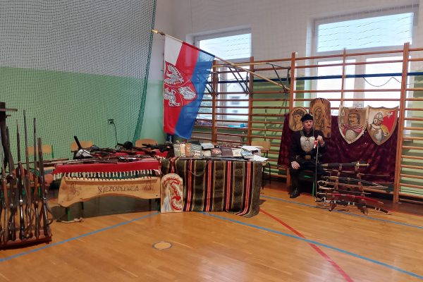 Stół z nagrodami i dekoracje Festiwalu Pieśni Patriotycznych w sali sportowej.