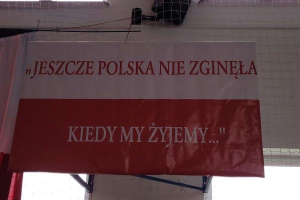 Biało-czerwony baner z fragmentem hymnu narodowego.