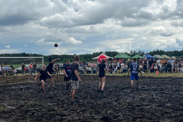 Zawodnicy podczas meczu piłki błotnej na mokrym, błotnistym boisku.