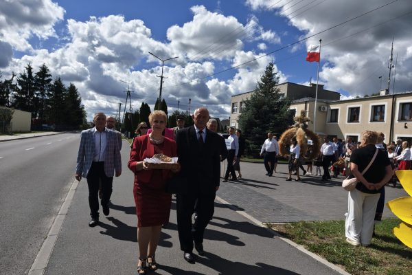Uczestnicy dożynek z wieńcami i tabliczkami przed kościołem.