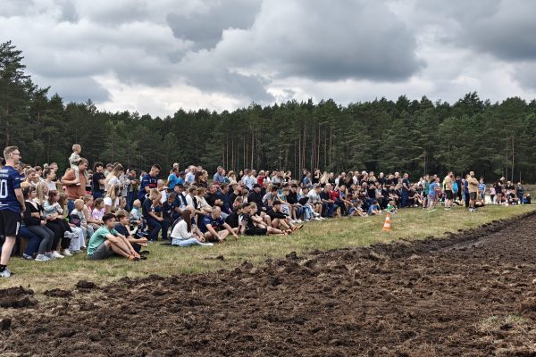 Publiczność obserwująca turniej przy błotnistym boisku.