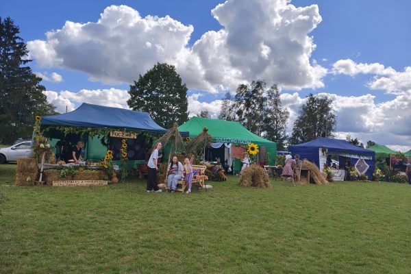 Plenerowe stoiska i scena ozdobione słomą, kwiatami i plonami.