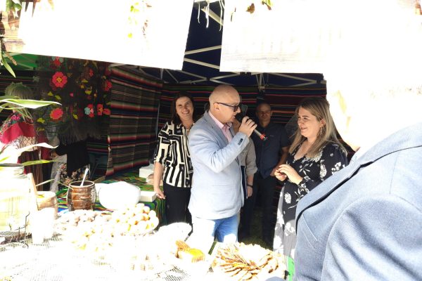 Uczestnicy dożynek przy stoisku z potrawami i dekoracjami z plonów.
