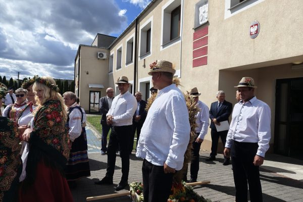 Uczestnicy dożynek z wieńcami i tabliczkami przed kościołem.