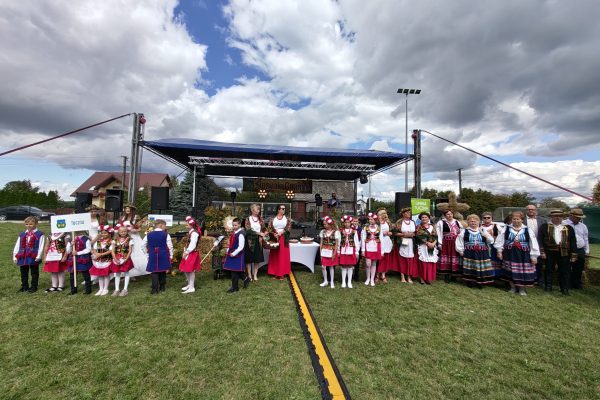 Korowód dożynkowy z wieńcami i uczestnikami w strojach ludowych.
