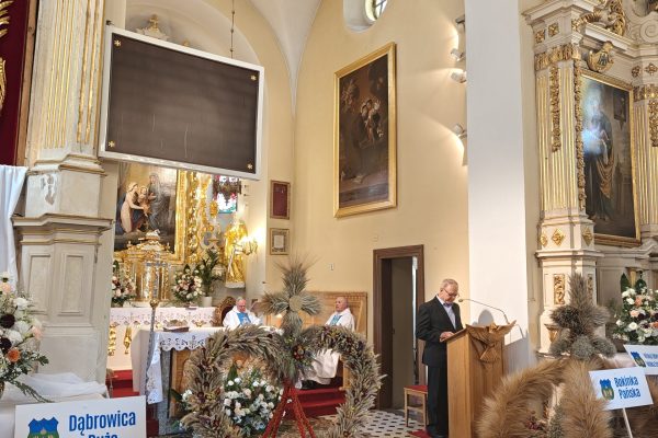 Wieńce dożynkowe i kosze z plonami przy ołtarzu.