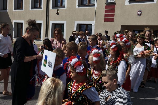 Uczestnicy dożynek z wieńcami i tabliczkami przed kościołem.
