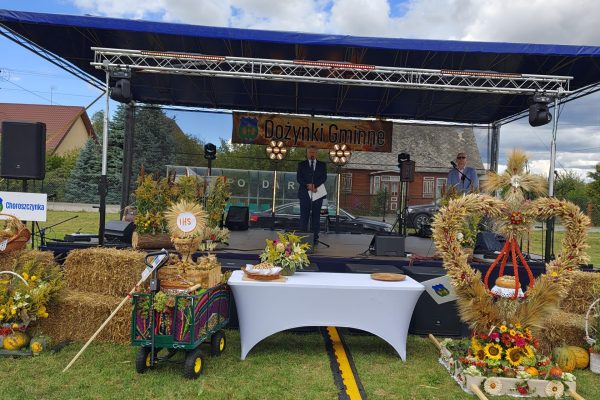 Plenerowe stoiska i scena ozdobione słomą, kwiatami i plonami.