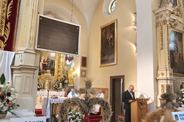 Wieńce dożynkowe i kosze z plonami przy ołtarzu.