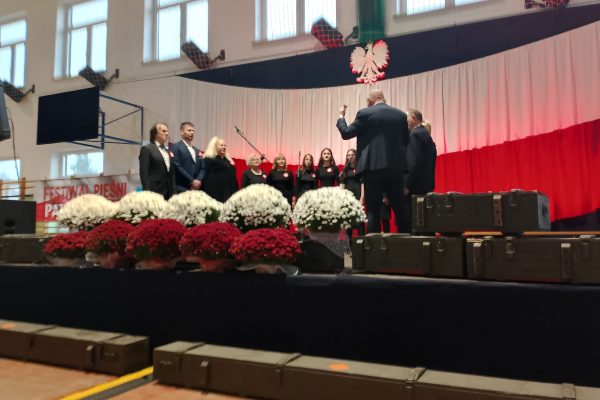 Uczestnicy przy mikrofonach na scenie Festiwalu Pieśni Patriotycznych.