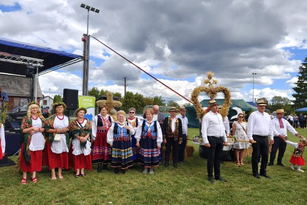 Korowód dożynkowy z wieńcami i uczestnikami w strojach ludowych.