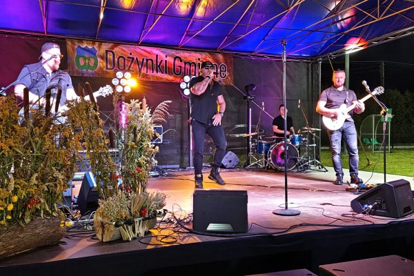 Muzycy podczas koncertu na oświetlonej scenie dożynek.